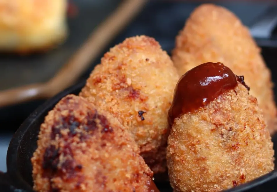Coxinhas recheadas com carne defumada servidas na frigideira com molho barbecue